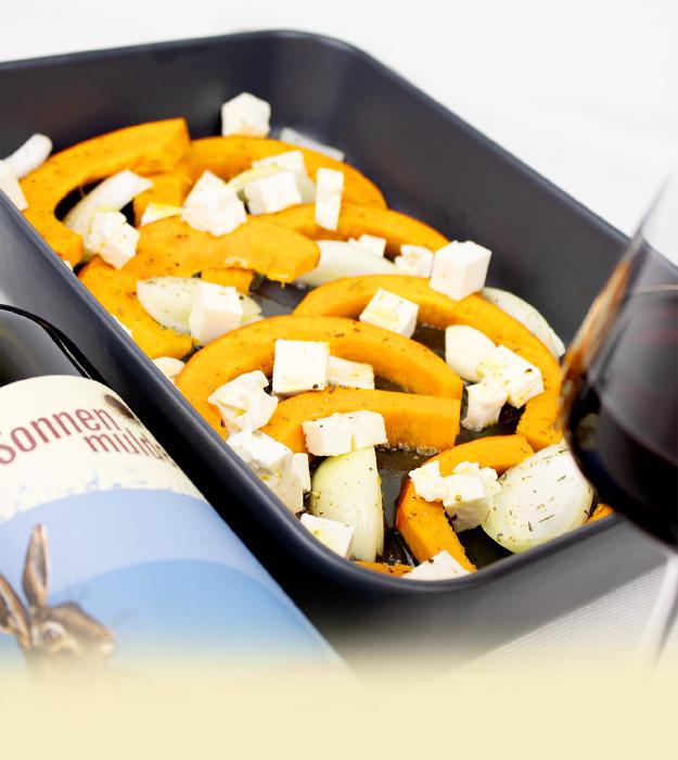 Fertig gekochtes Gericht in einer Backform, daneben ein Glas Blaufränkisch und die zugehörige Flasche.