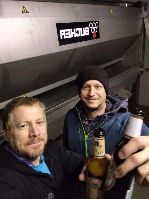 Selfie of two people holding beer bottles.